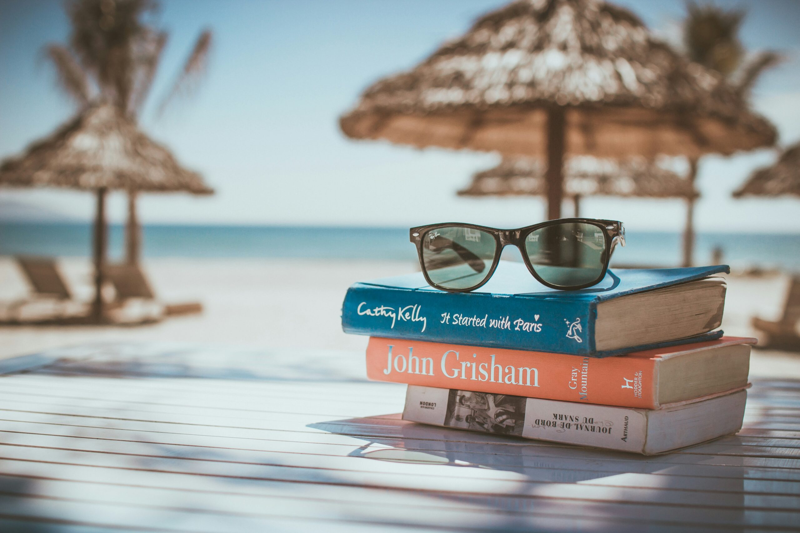summer read-a-thon fundraising idea A stack of books in a cabana on the beach