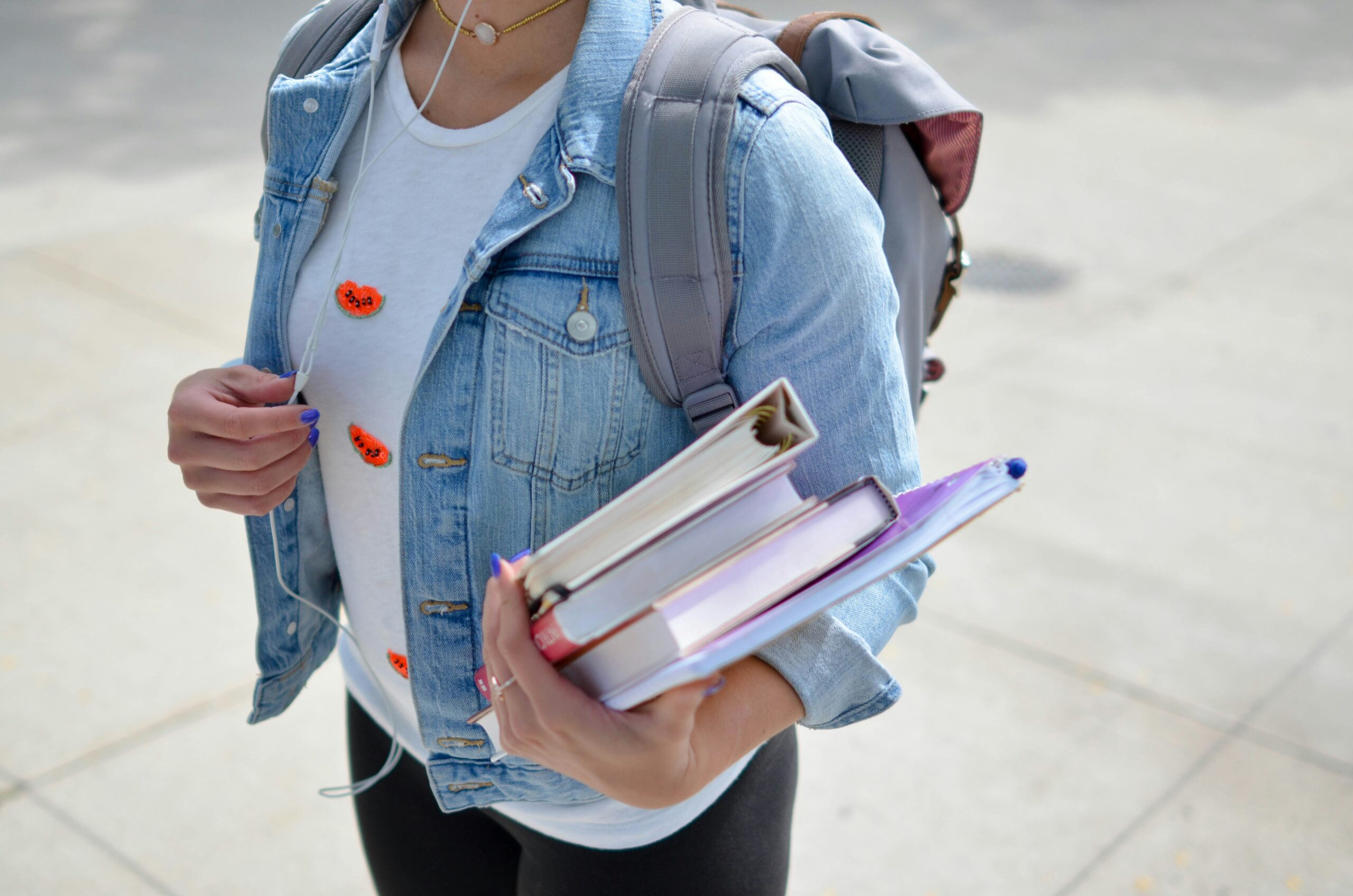 a child wearing a back pack holding books