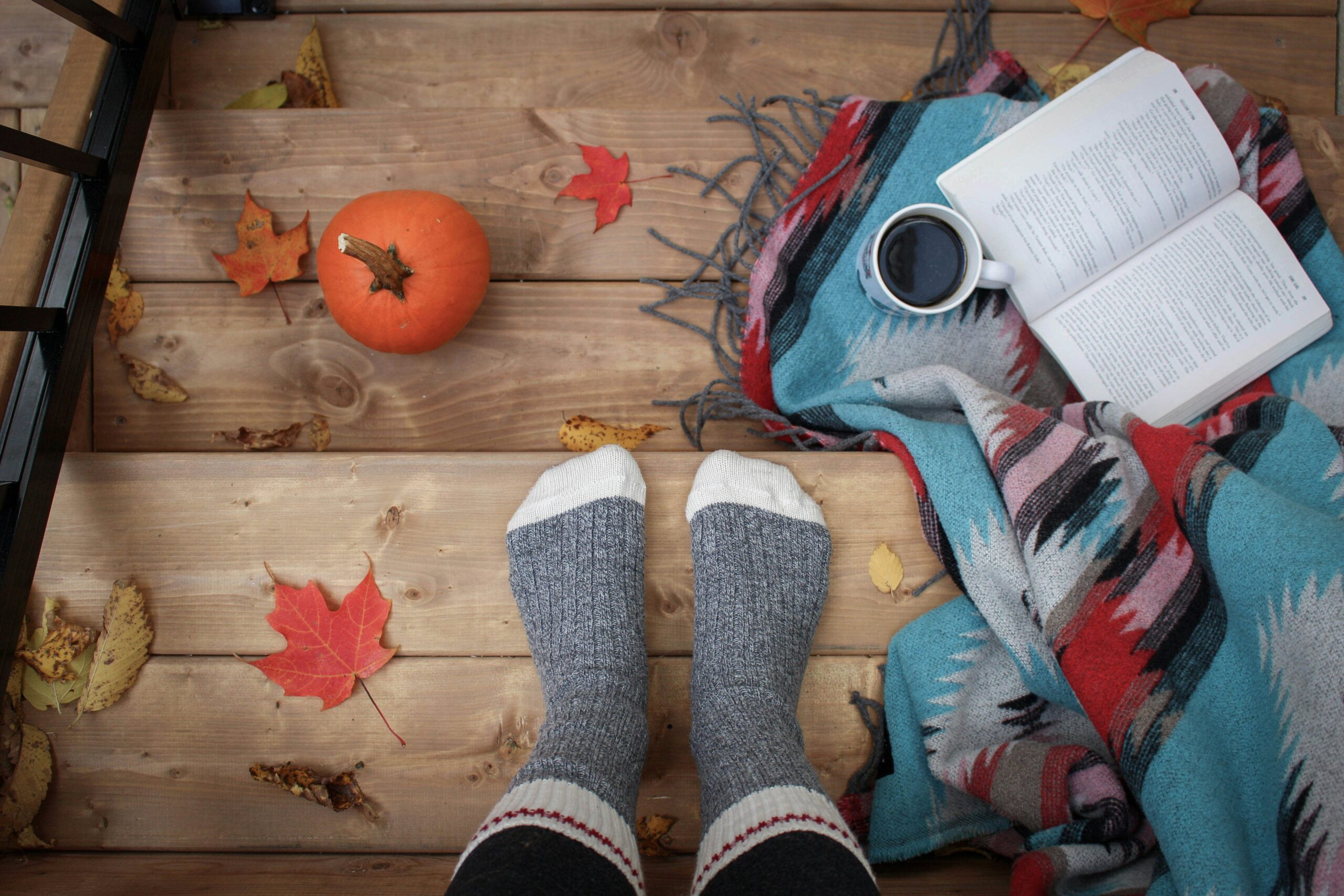 Fall equinox Fundraising Ideas a cozy fall scene with socked feet, pumpkins, and an open book