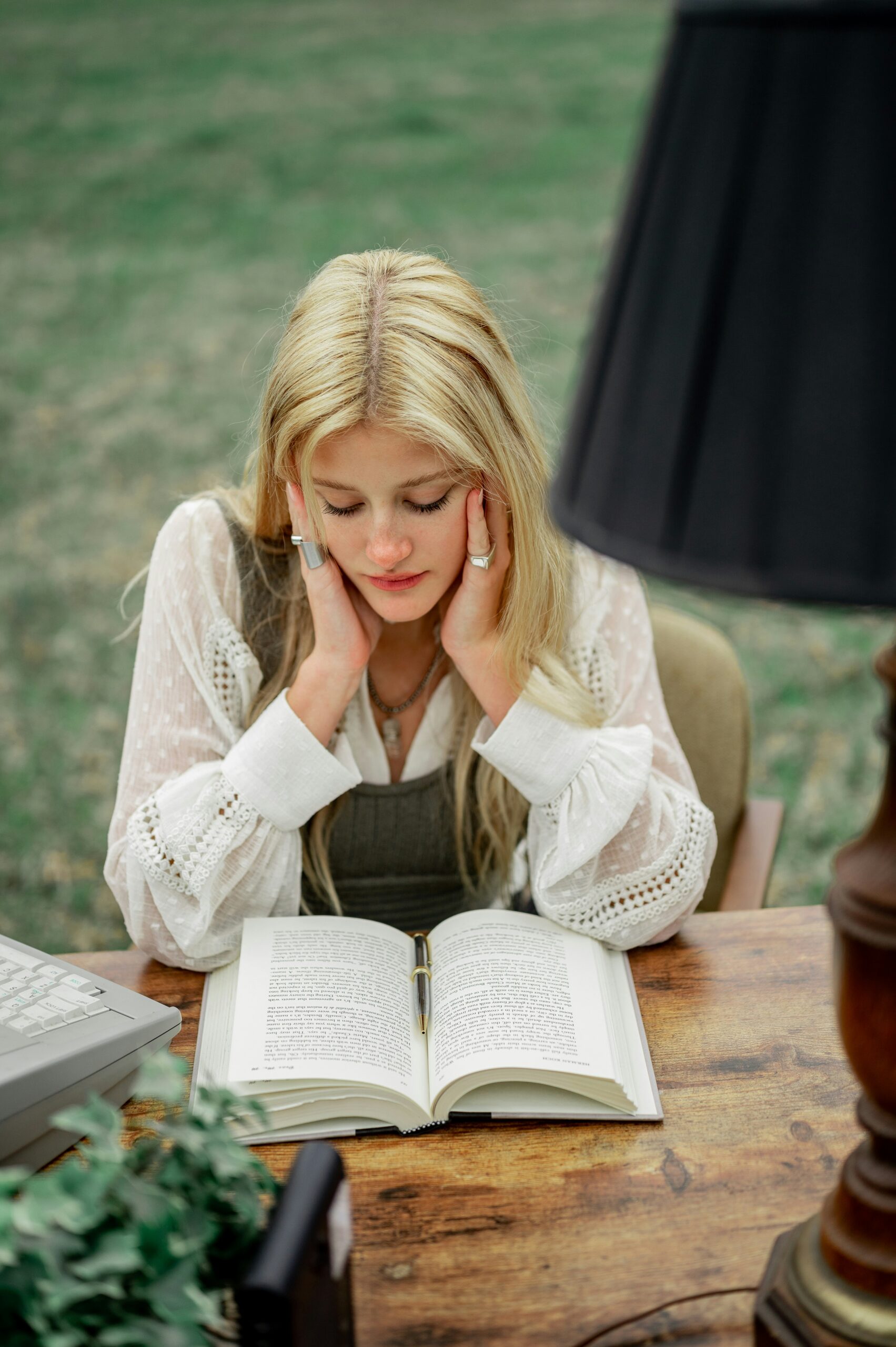 Young woman reading a book at an outdoor desk, deeply focused